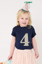 A girl celebrating her 4th birthday wearing a navy cotton t-shirt with the number 4 sewn on the front cut from liberty floral Nazanin print.
