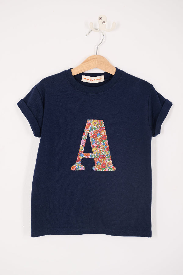 A personalised kids navy t-shirt with an initial cut from nell annie and may liberty floral print sewn on the front.
