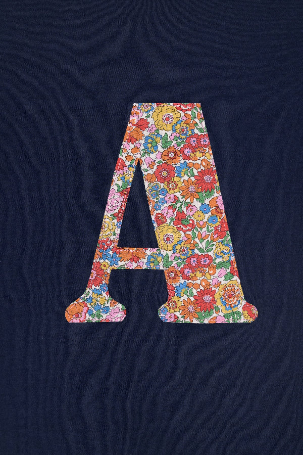 A close up of a personalised kids navy t-shirt with an initial cut from nell annie and may liberty floral print sewn on the front. 
