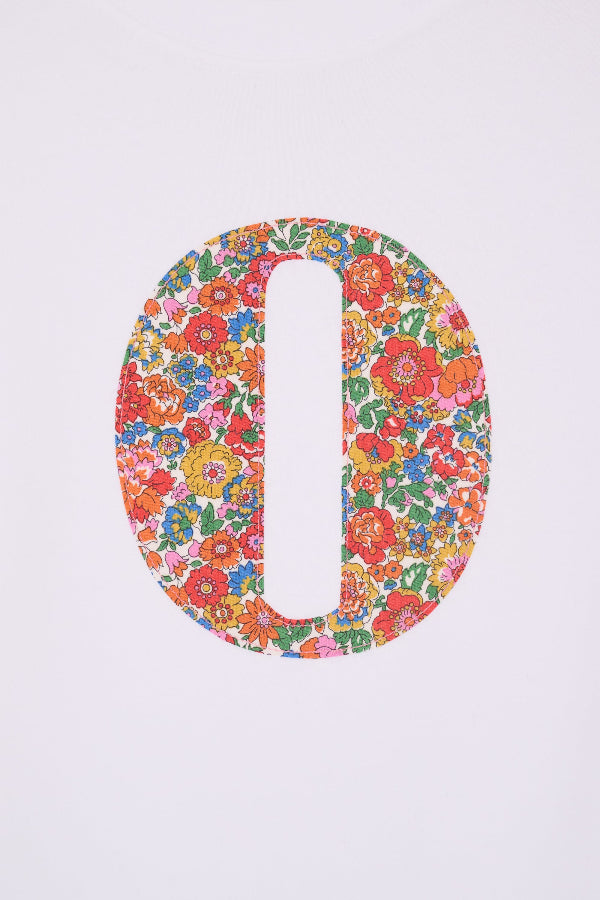 A close up of a summery personalised white cotton t-shirt with her initial cut from Nell Annie and May floral liberty fabric.