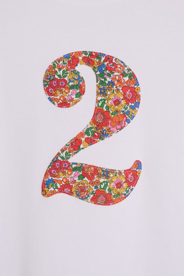 A close up of the stitching on a white cotton birthday t-shirt with the number 2 sewn on the front cut from liberty Nell Annie and May fabric