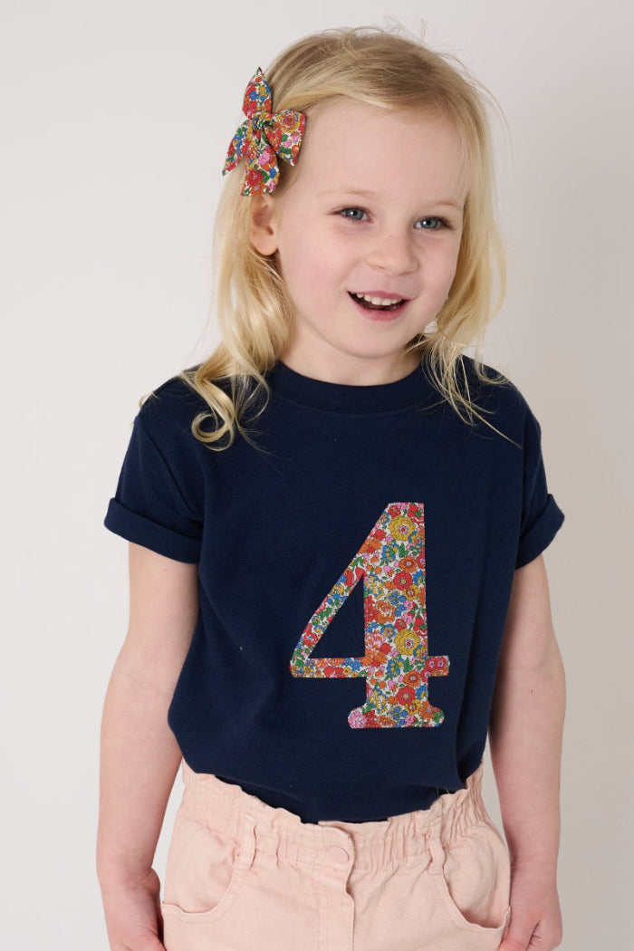 a 4 year old birthday girl wearing a navy cotton t-shirt with the number 4 sewn on the front cut from liberty floral Nell Annie and May print.
