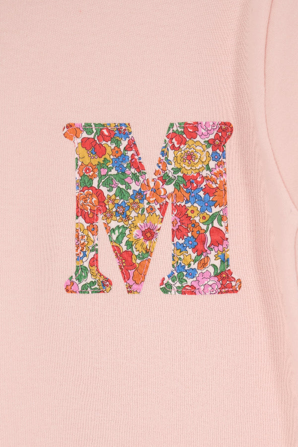 a pale pink t-shirt with a Liberty Nell Annie and May floral small initial on the front, a close up of the stitching