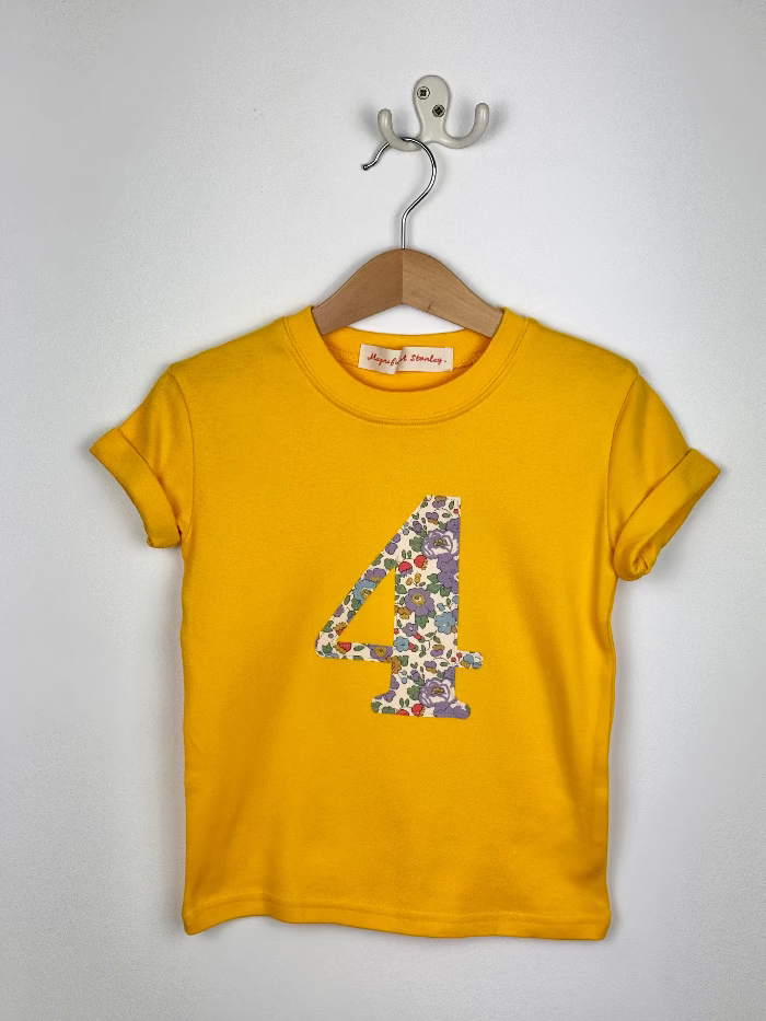 Yellow t-shirt with floral number 4 on a hanger against a white background