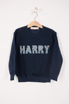 a navy sweatshirt with the name 'HARRY' sewn on it cut from Liberty print card fabric