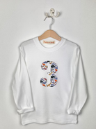 White sweatshirt with colorful '3' design on a hanger against a white background