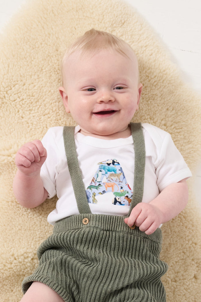 a smiling baby wearing a personalised baby bodysuit made from Liberty zoo animal print Quey 2