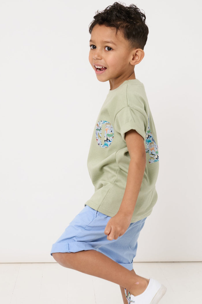a 4 year old boy wearing a sage green t-shirt with a small initial on the front cut from zoo animal Liberty print