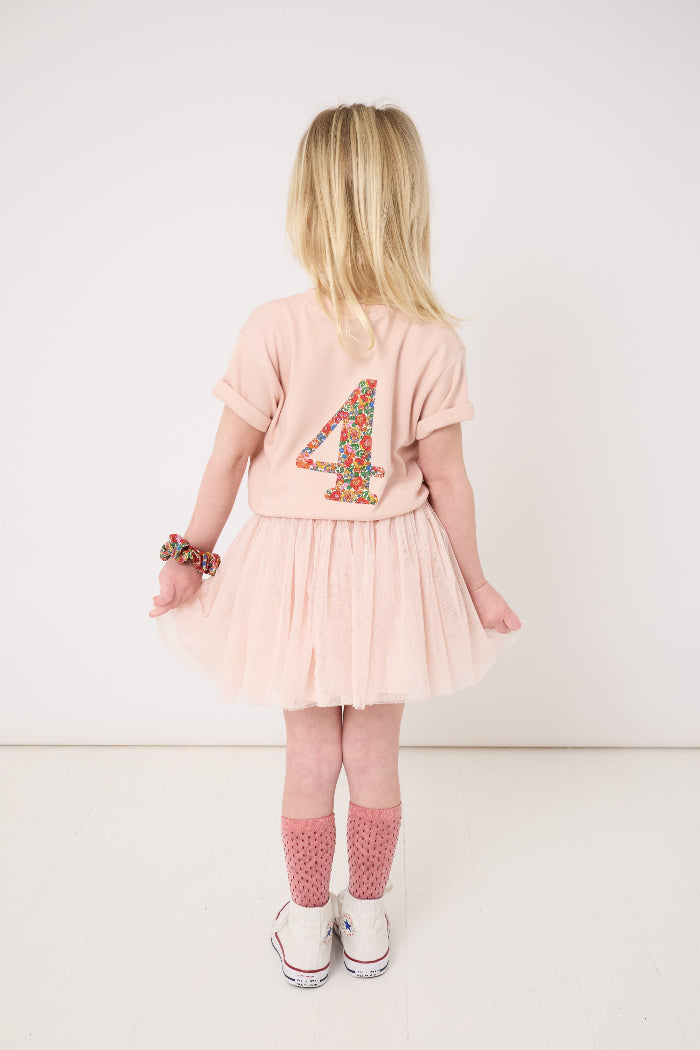 Child wearing a pink dress with number 4 design on a white background