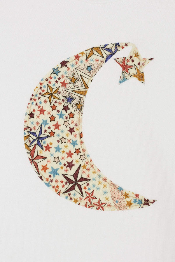 A white cotton babygrow with a moon and hanging star sewn on the front, cut from Adelajda starry Liberty print. a close up of the stitching.