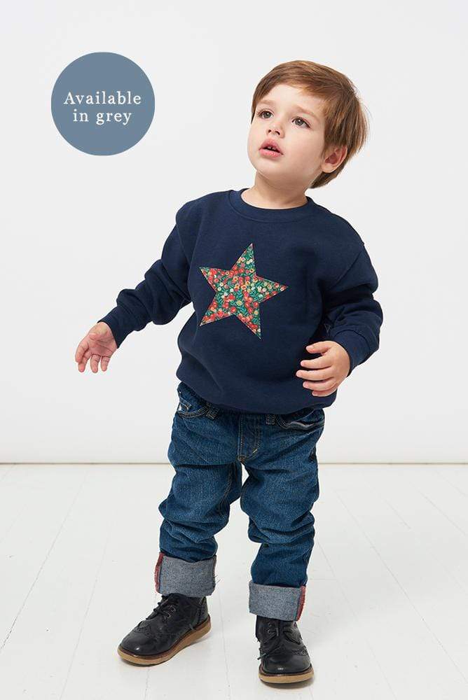 A little boy wearing a Christmas star jumper navy sweatshirt with a liberty Wiltshire star on the front