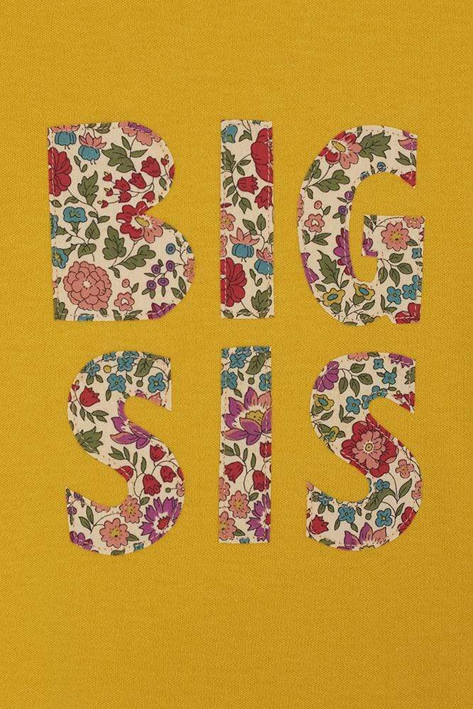 A yellow cotton t-shirt with the words big sis sewn on the front in D'Anjo liberty print.