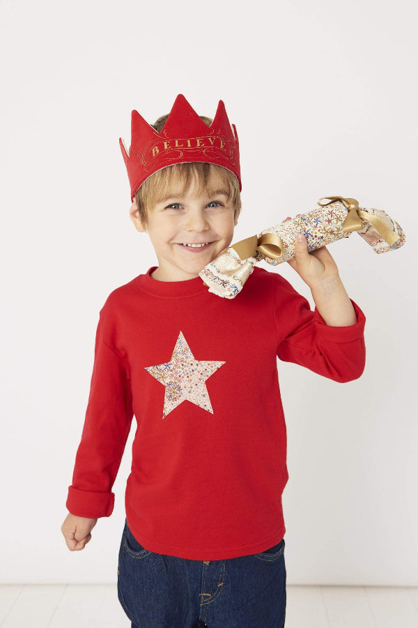 a smiling 5 year old boy wearing a Magnificent Stanley Red star kids Christmas T-Shirt in Adelajda Liberty Print